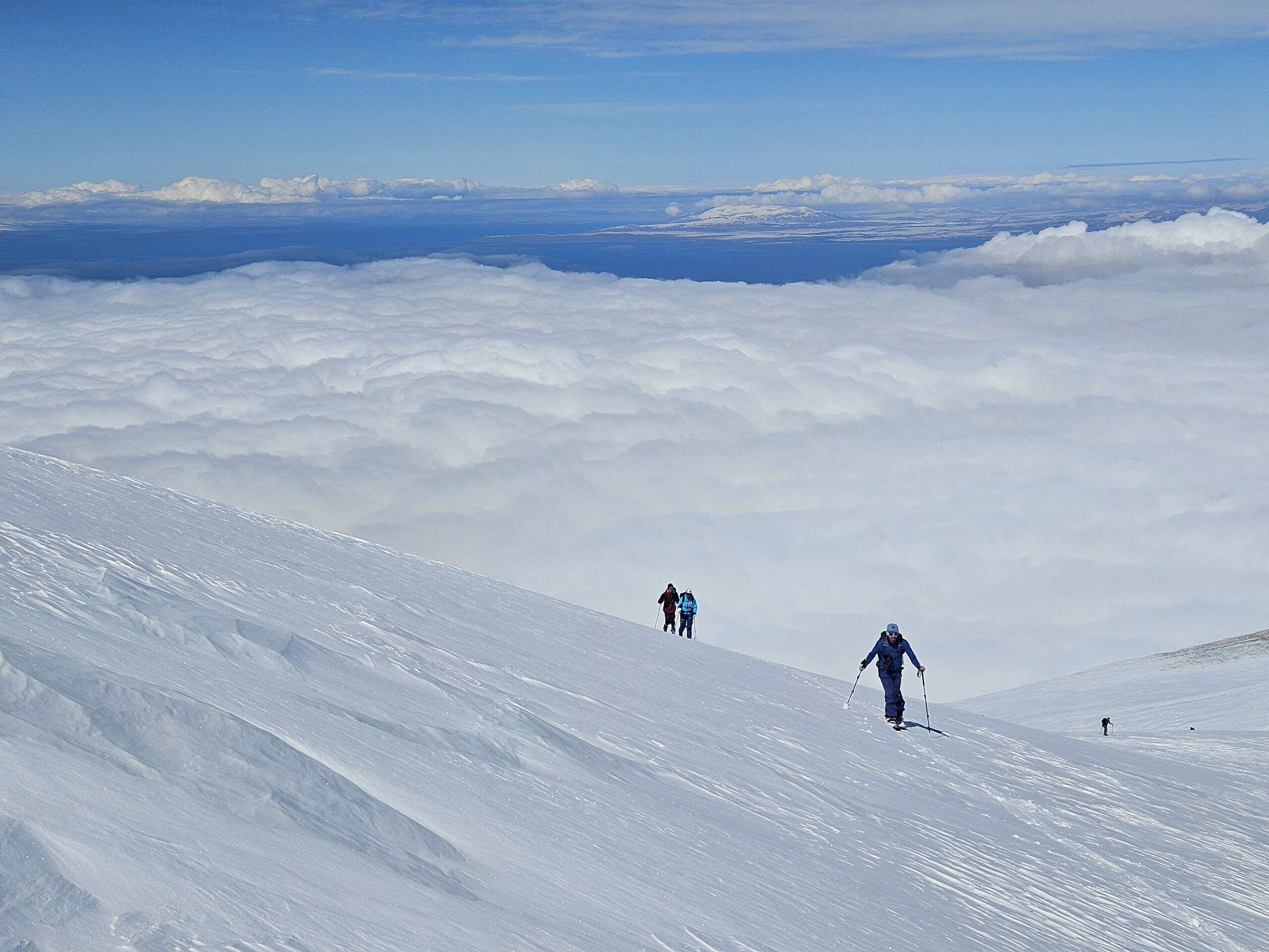 A ski touring ascent along the exposed snow ridge on Artos Dağı, with a sweeping view down to the glistening Lake Van and the clouds in the valley.